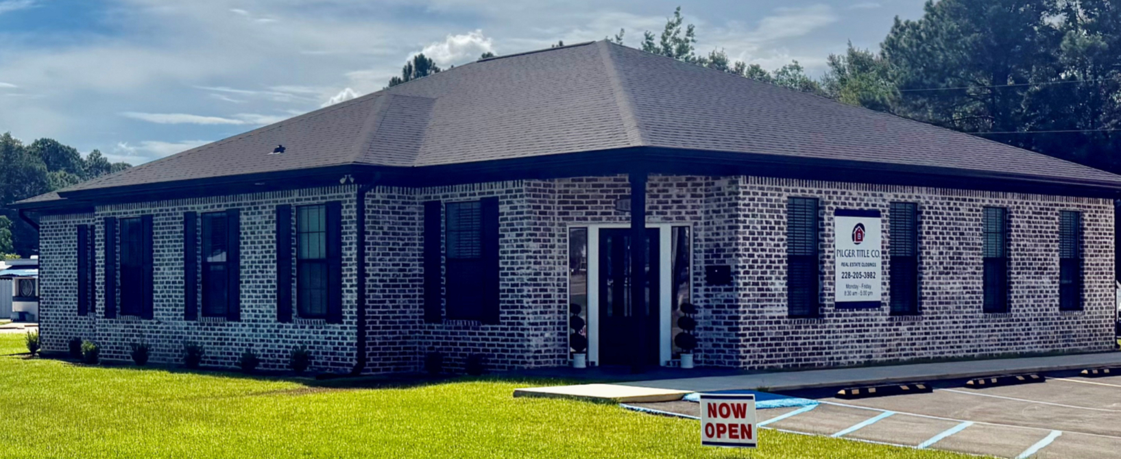 The brick Pilger Title Co. office in Gautier with its sign and NOW OPEN banner