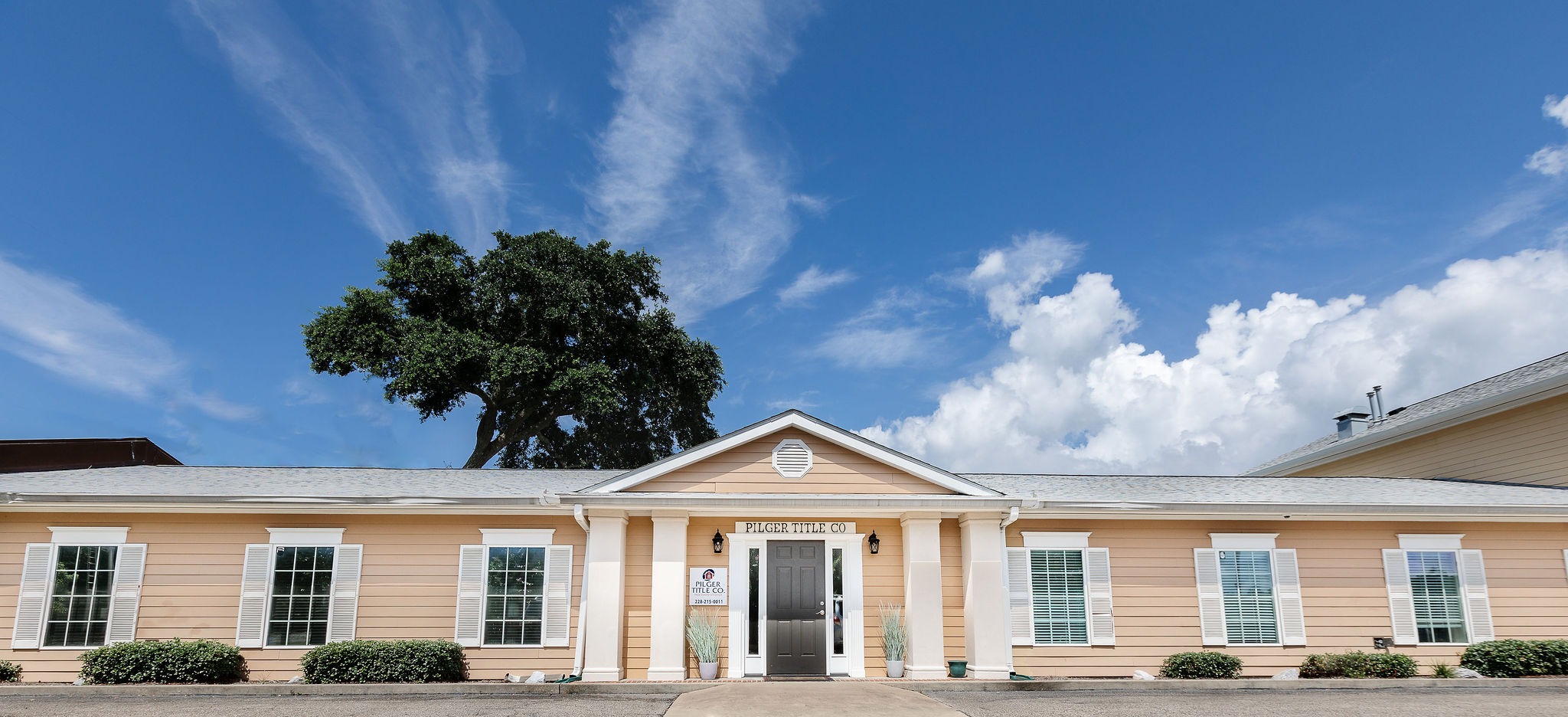 The Pilger Title Co. headquarters on Bienville Blvd in Ocean Springs — a peach colonial-style office under a live oak